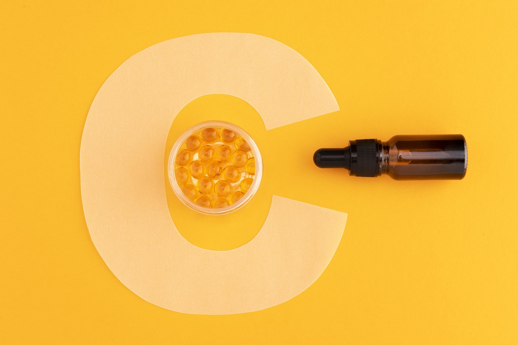 cápsulas de vitamina C ao lado de um frasco de remédio com conta gotas