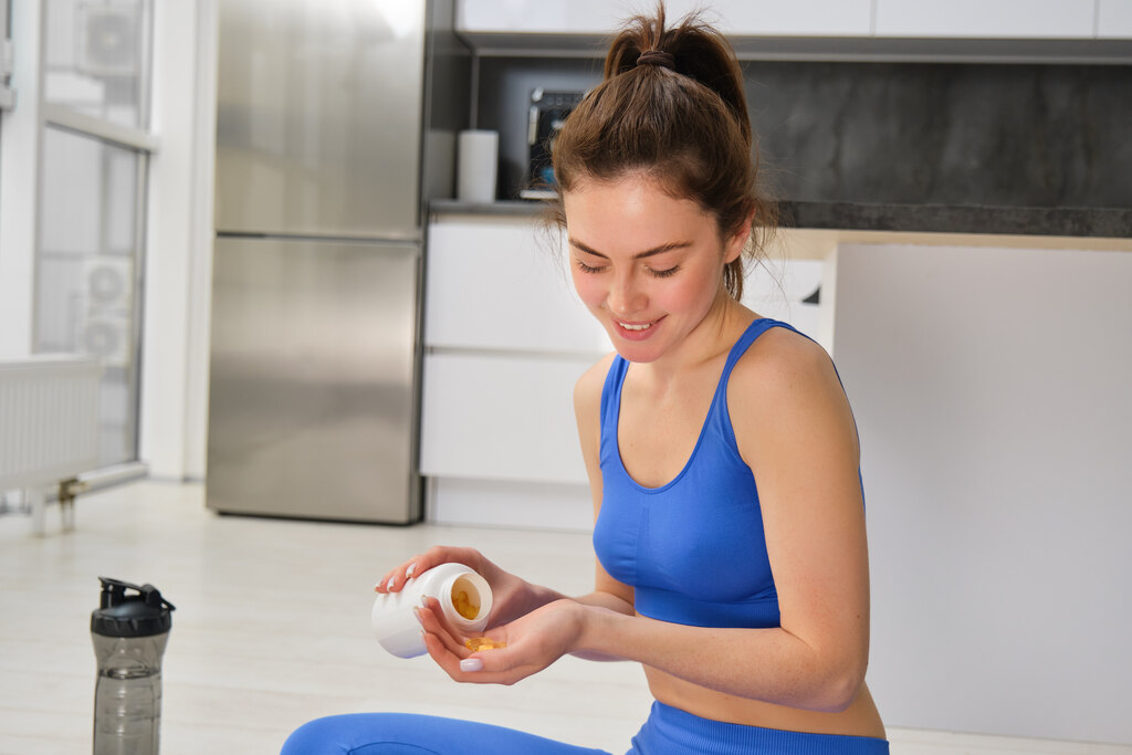 mulher com roupas de academia se preparando para ingerir capsulas de suplemento alimentar