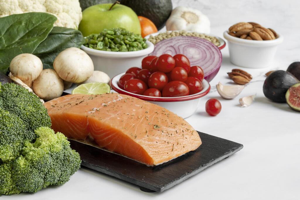 Alimentos ricos em ômega 3 como salmão, brócolis, tomate, nozes e vegetais frescos para uma alimentação saudável.